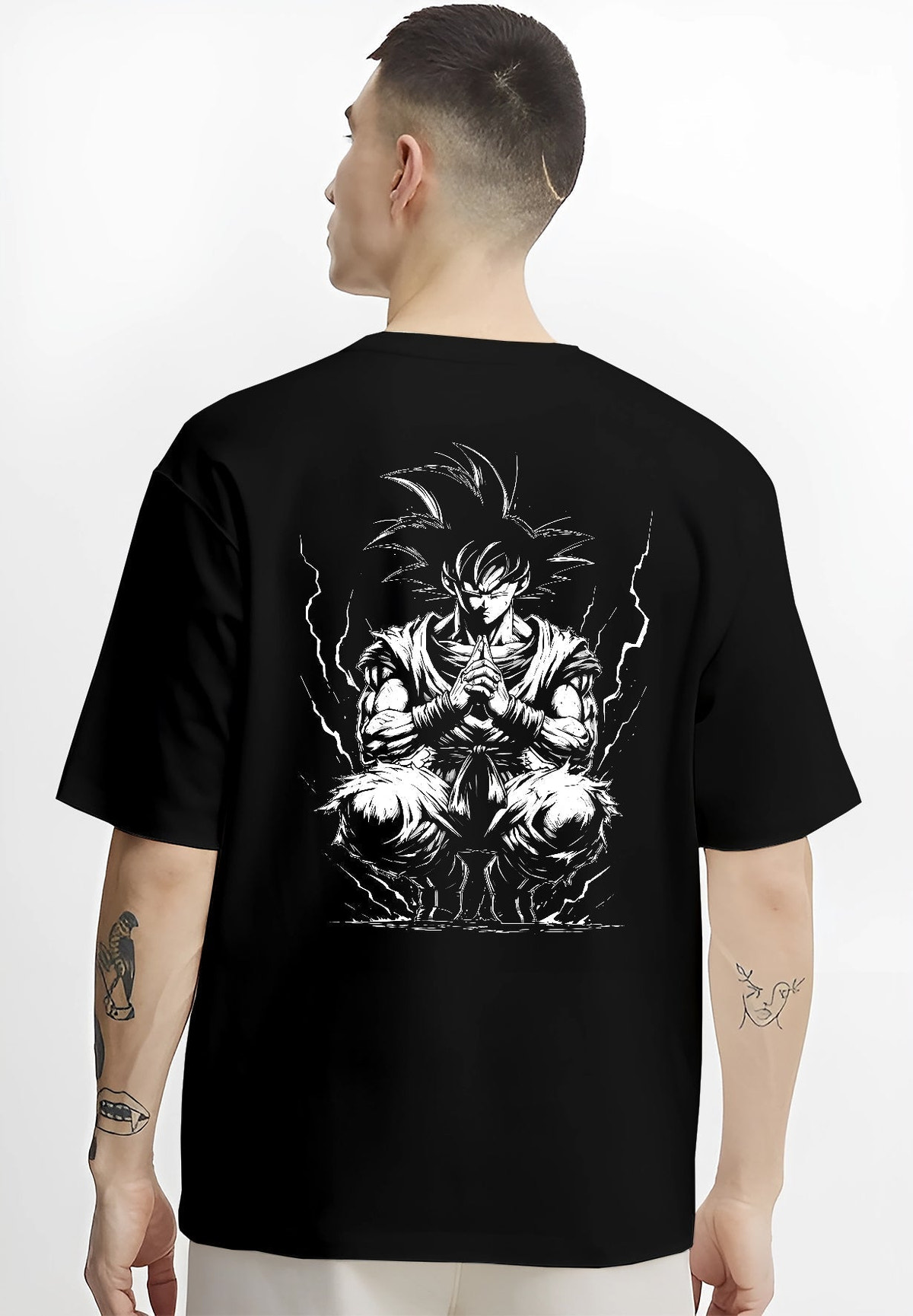 Black T-shirt worn by a male model, back view, featuring Dragon Ball Goku anime poster inspired design in meditation pose with glowing aura in retro manga graphic style.