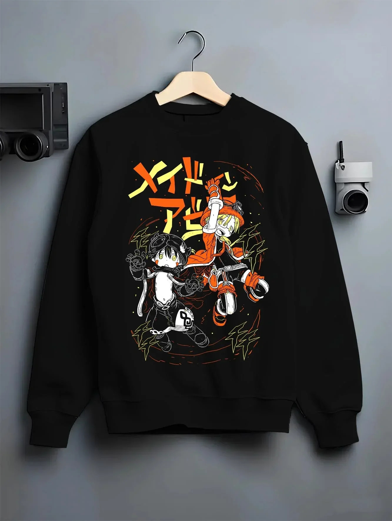 Black crewneck sweatshirt on a hanger against a grey wall, featuring Riko and Reg retro manga lightning artwork in clean modern streetwear graphic.