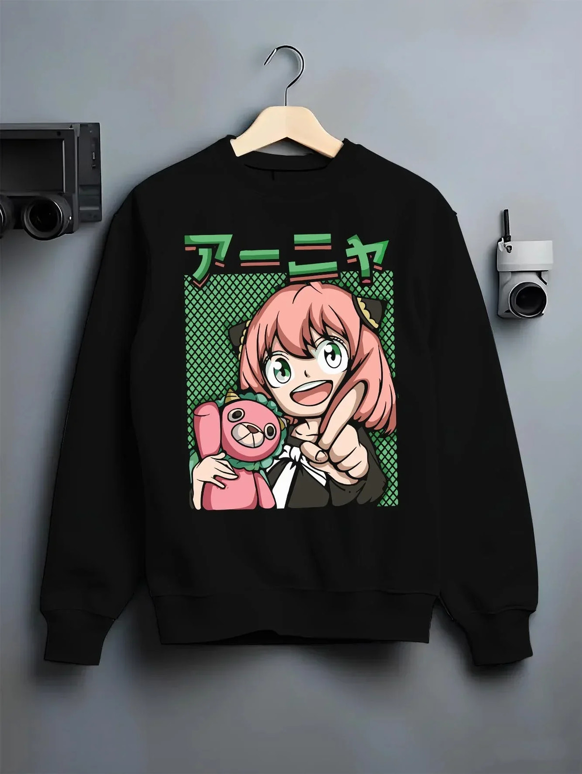 Black crewneck sweatshirt on hanger with Anya Forger Hoodie Spy x Family Retro Pop Art Smile graphic bold anime graphic.