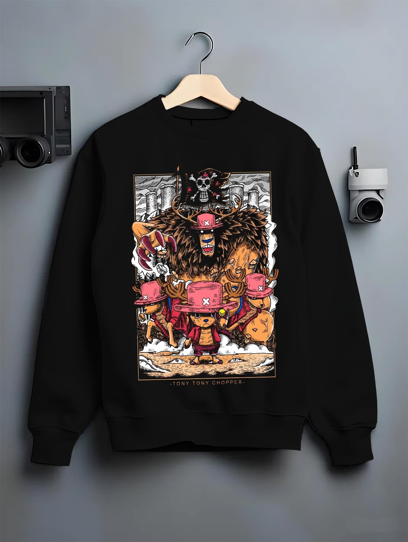 Black crewneck sweatshirt on a hanger against a grey wall, featuring One Piece Chopper anime poster inspired monster form design in retro manga battle artwork style.