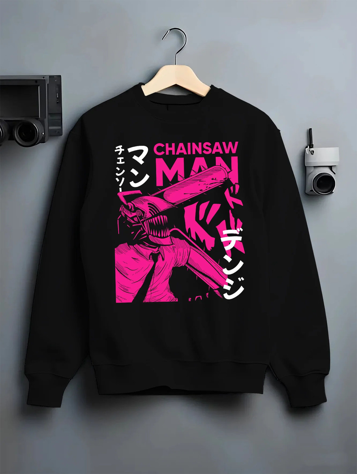 Black crewneck sweatshirt on hanger showing Chainsaw Devil / Denji from Chainsaw Man: magenta chainsaw-head graphic