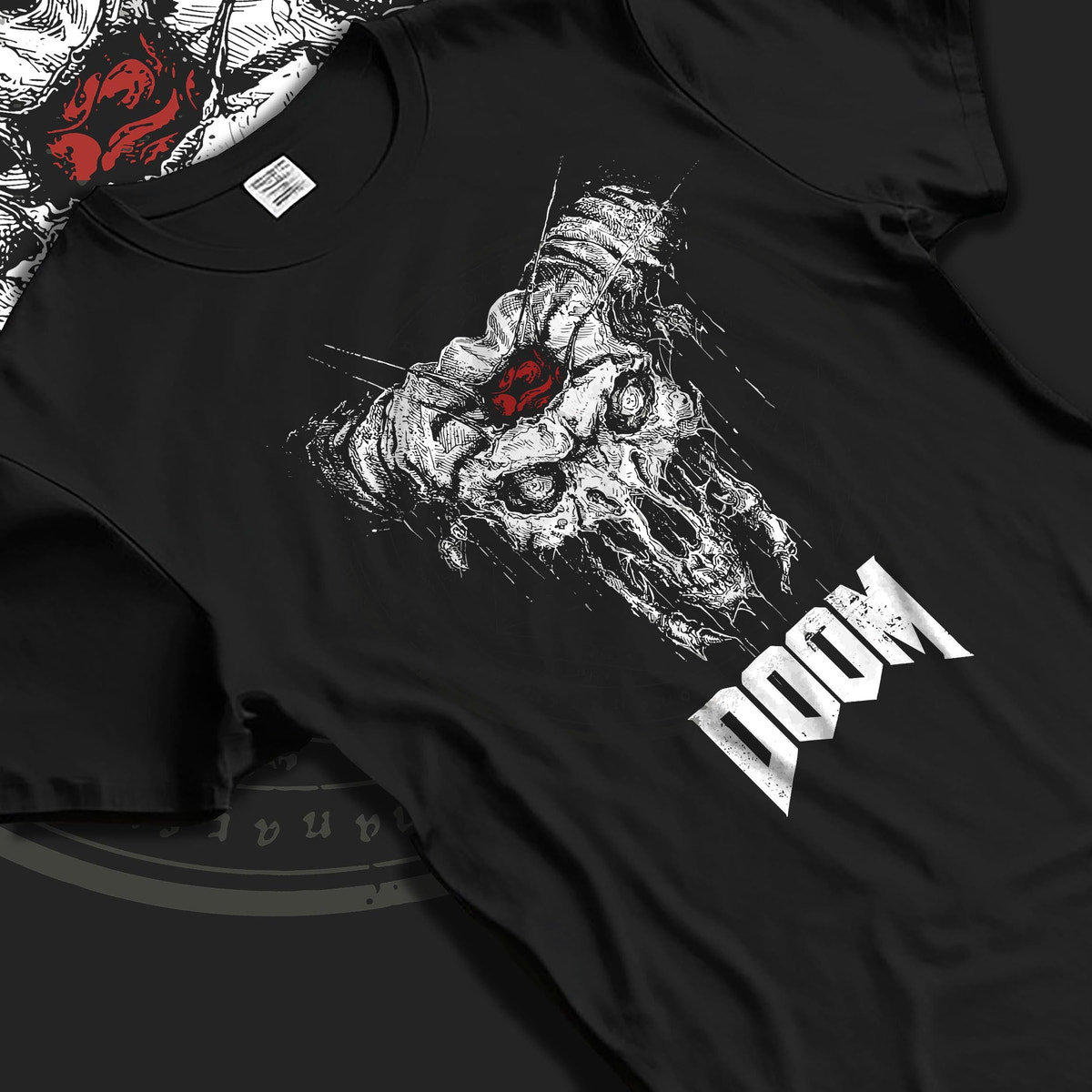 Black T-shirt laid flat with natural fabric folds, featuring DOOM demonic skull graphic with horns, distressed horror design and apocalyptic retro style.