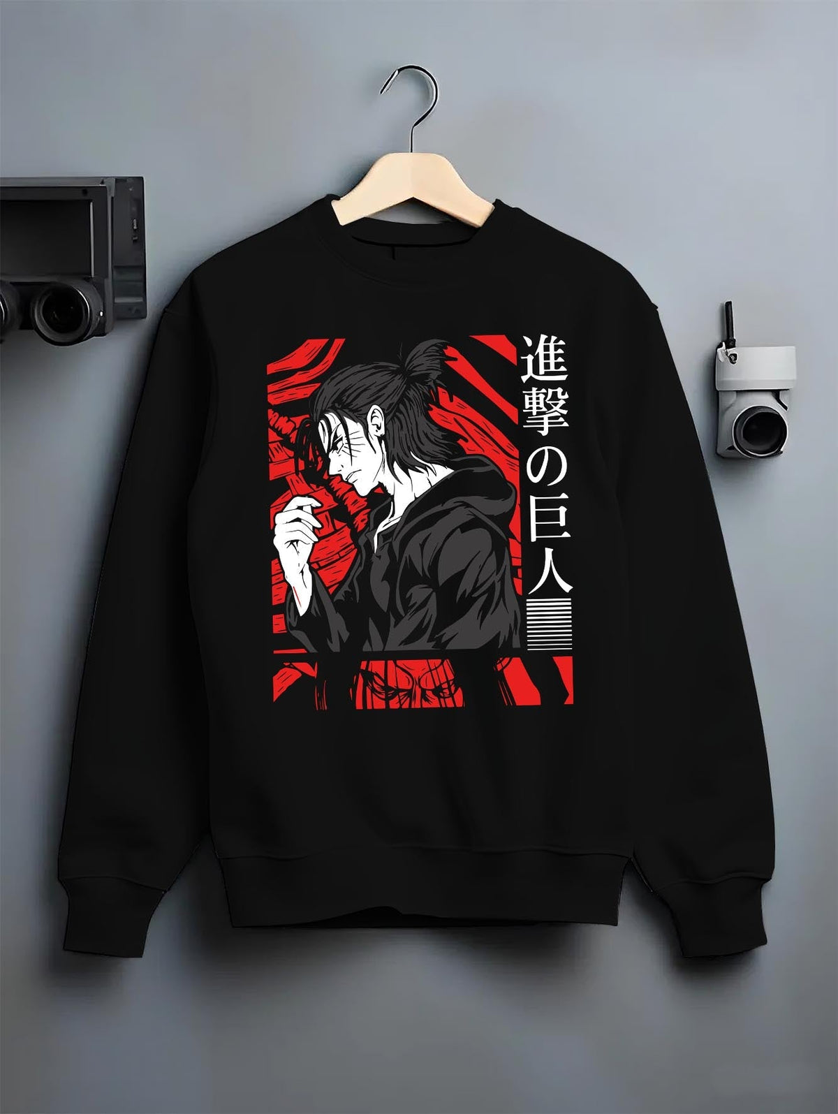 Black crewneck sweatshirt on a hanger against a grey wall, featuring Attack on Titan Eren Yeager anime poster inspired portrait graphic with retro manga style and red design.