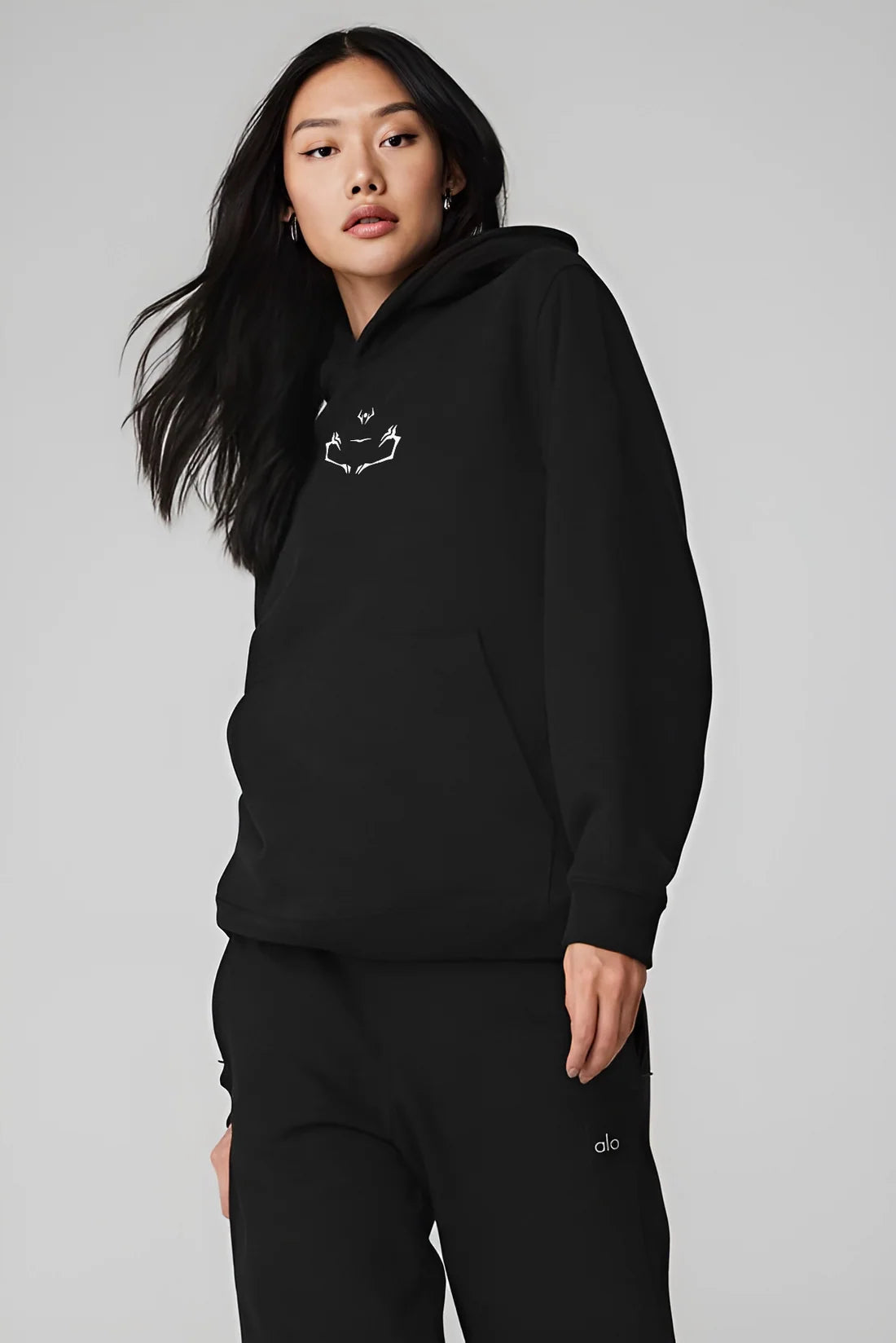 Female model wearing black Sukuna symbol hoodie from Jujutsu Kaisen anime, premium Japanese anime clothing by Kunai for streetwear fans.