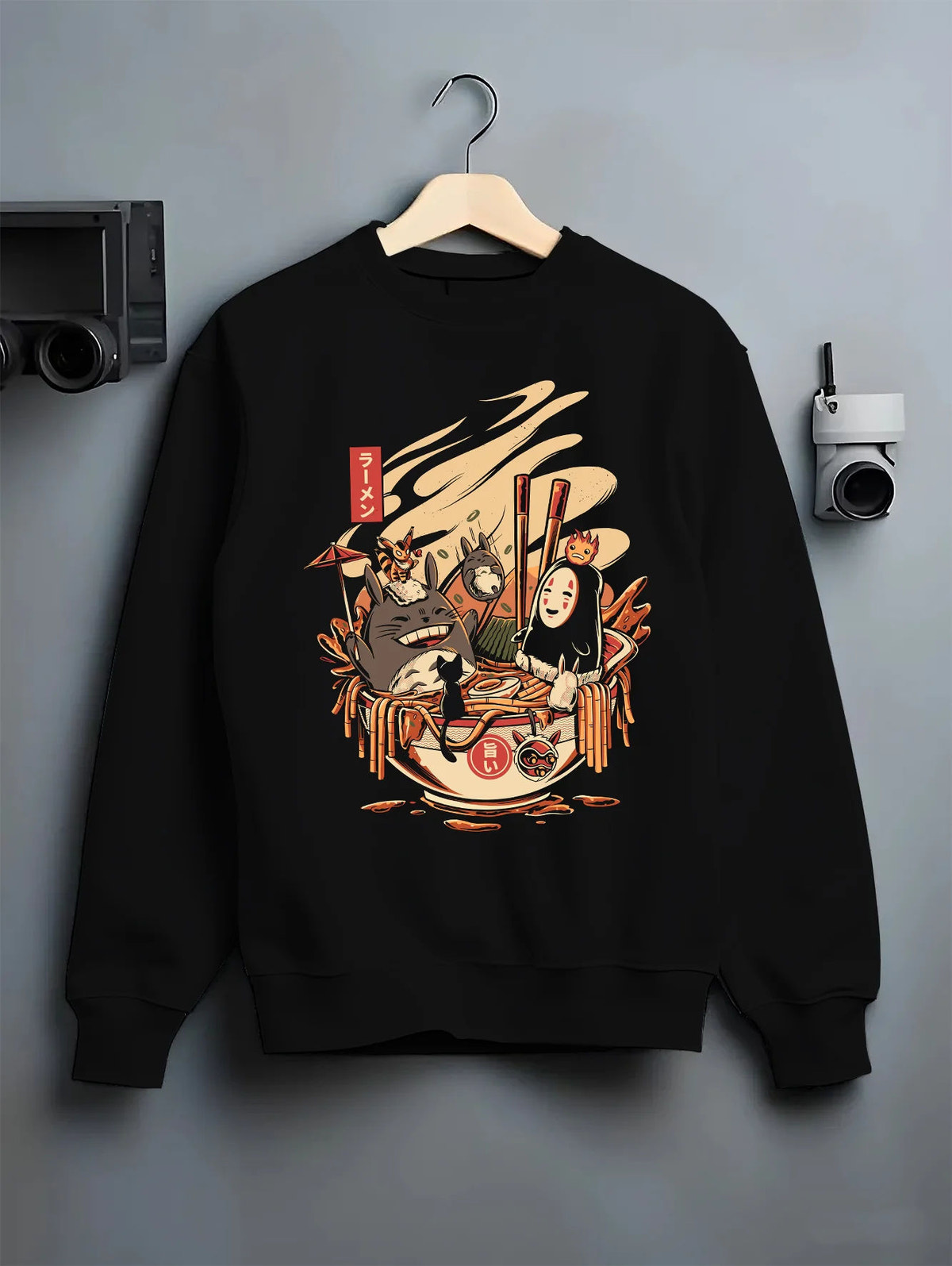 Black crewneck sweatshirt on hanger showing Totoro, No-Face, Calcifer from Studio Ghibli: ramen crossover