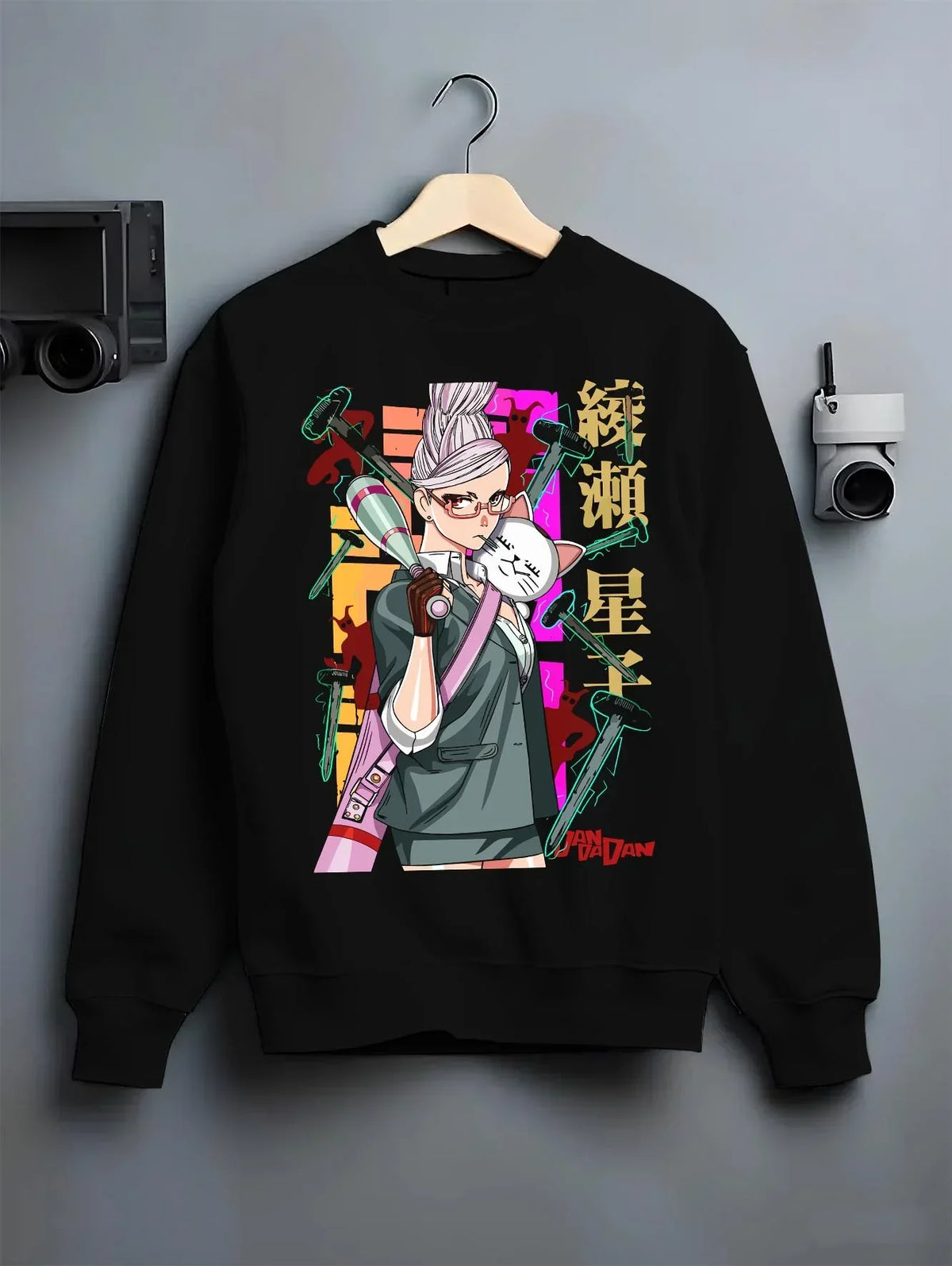 Black crewneck sweatshirt on a hanger against a grey wall, featuring retro streetwear graphic of Aira Shiratori from Dandadan anime.