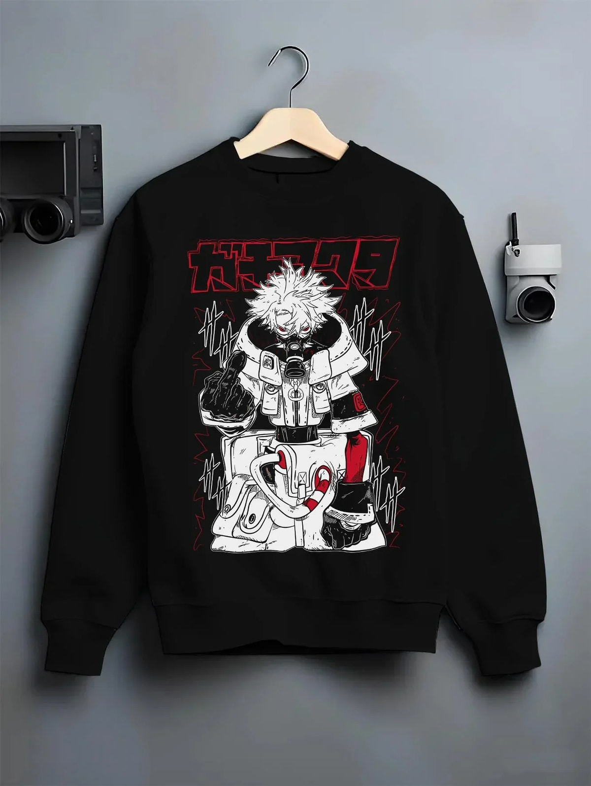Black crewneck sweatshirt on hanger against grey wall, showcasing retro manga graphic of Rudo from Gachiakuta with dark manga panel artwork.
