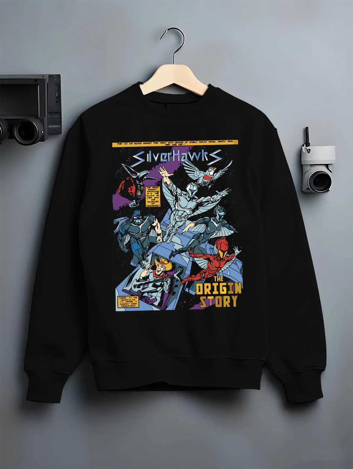 Black crewneck sweatshirt on hanger featuring SilverHawks origin story team artwork.