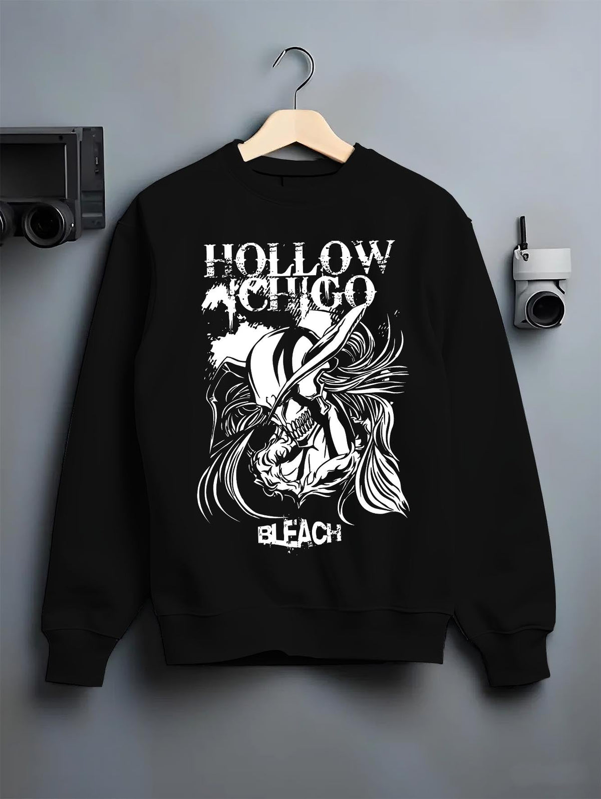 Black crewneck sweatshirt on a hanger against a grey wall, featuring Hollow Ichigo Bleach retro manga graphic design with dark shonen battle artwork.