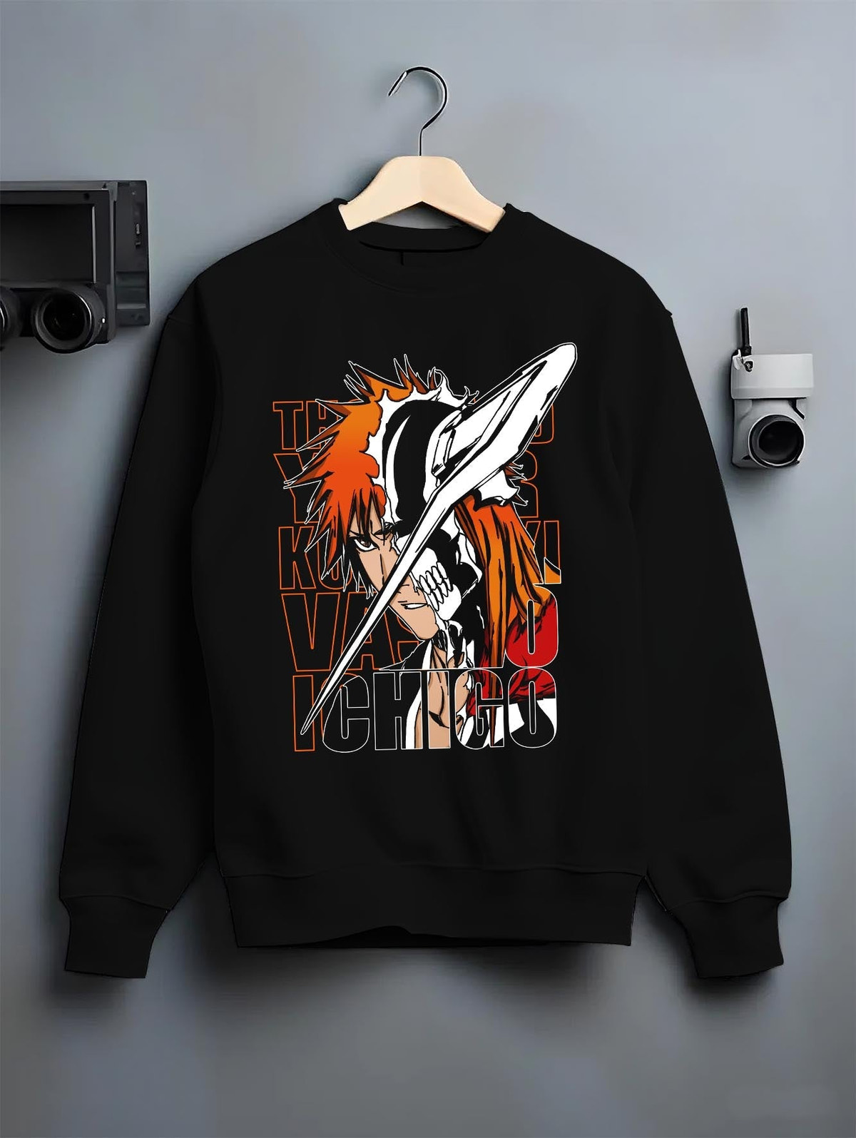 Black crewneck sweatshirt on a hanger against a grey wall, featuring Bleach Ichigo Kurosaki Vasto Lorde dark manga panel inspired artwork with retro streetwear graphic.