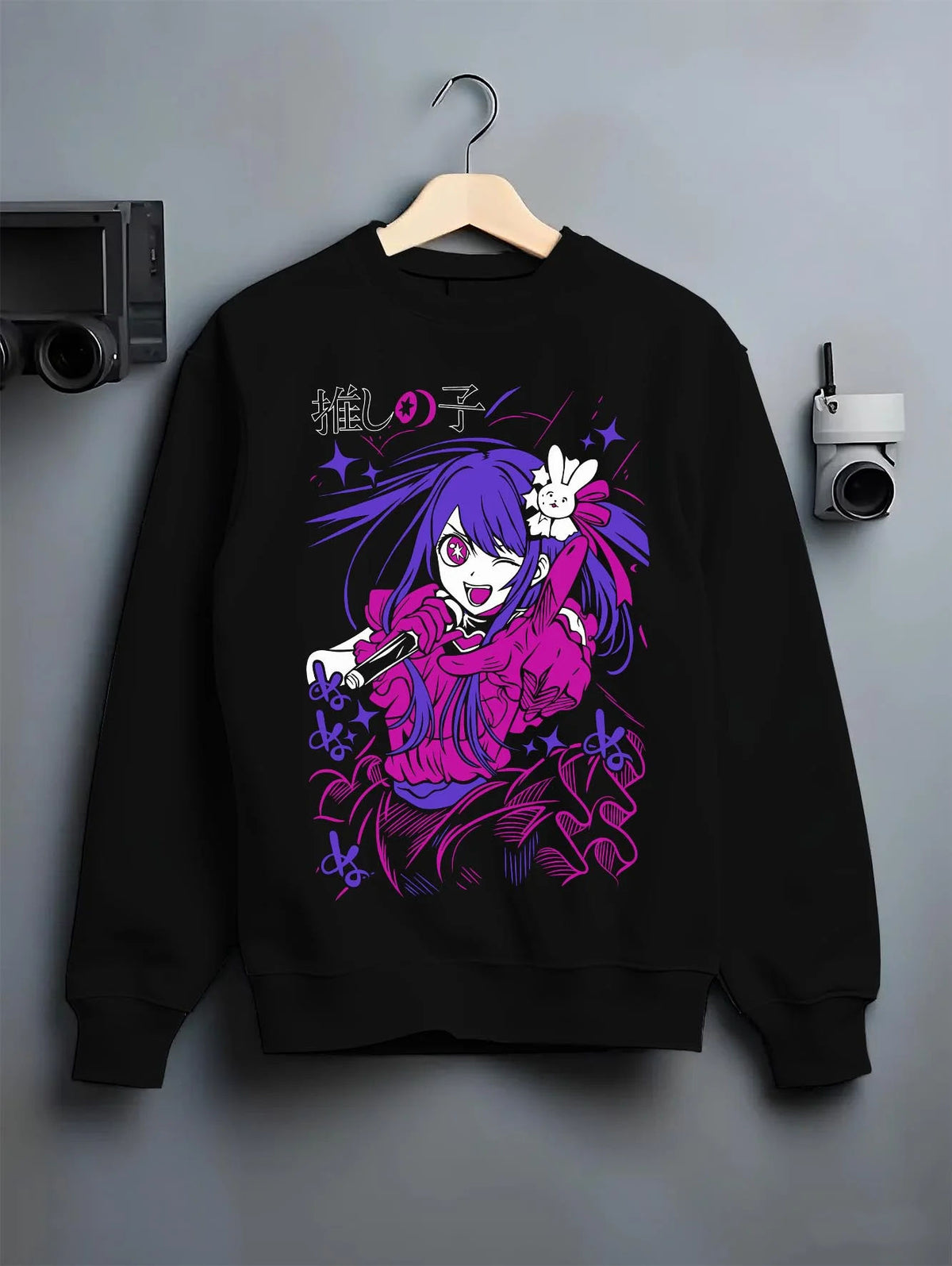 Black crewneck sweatshirt on hanger featuring Ai Hoshino microphone stage portrait Oshi no Ko artwork.