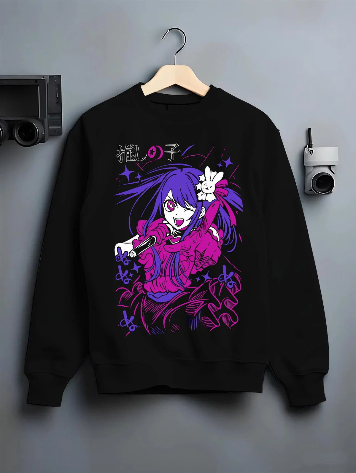 Black crewneck sweatshirt on hanger featuring Ai Hoshino microphone stage portrait Oshi no Ko artwork.