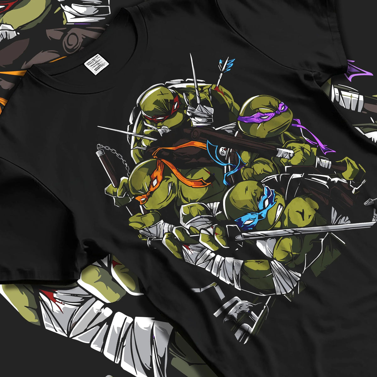 Black T-shirt laid flat with natural folds featuring Teenage Mutant Ninja Turtles sewer team TMNT artwork.