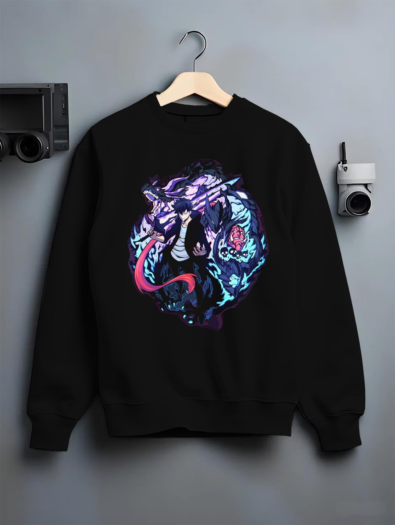 Black crewneck sweatshirt on a hanger against a grey wall, featuring Jinwoo Sung shonen battle character design with sword and neon shadow dragon style.