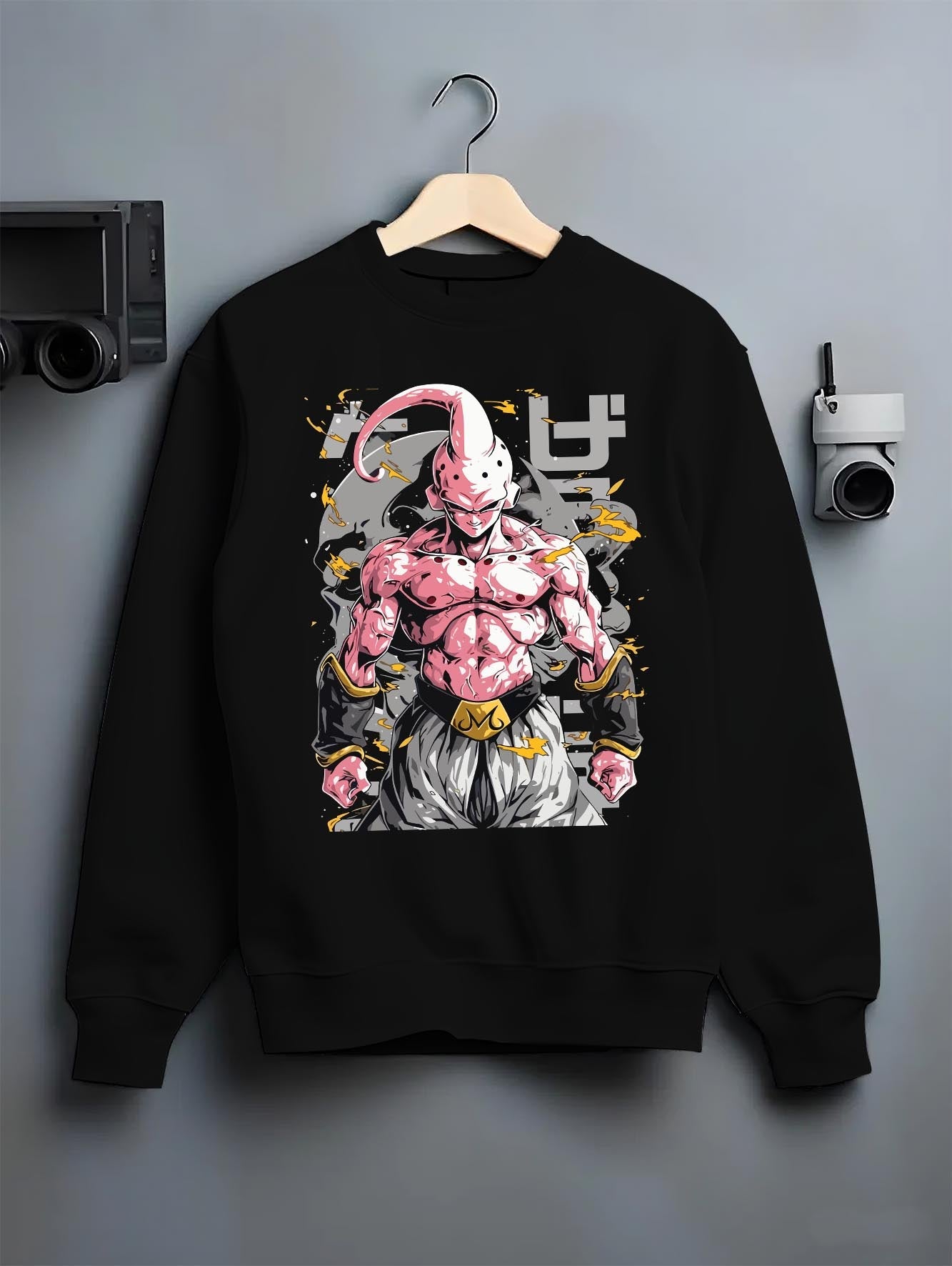 Black crewneck sweatshirt on a hanger against a grey wall, featuring Dragon Ball Majin Buu anime poster inspired design with shonen battle pose and lightning aura effects.