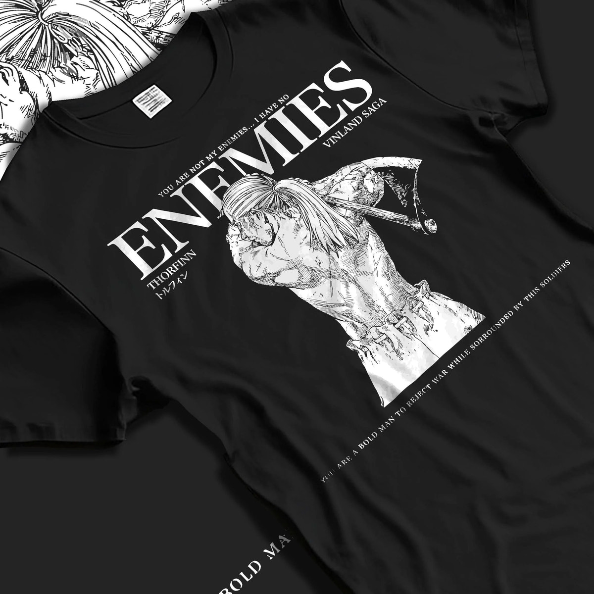 Black T-shirt laid flat with natural folds featuring Thorfinn enemies Viking revenge Vinland Saga artwork.