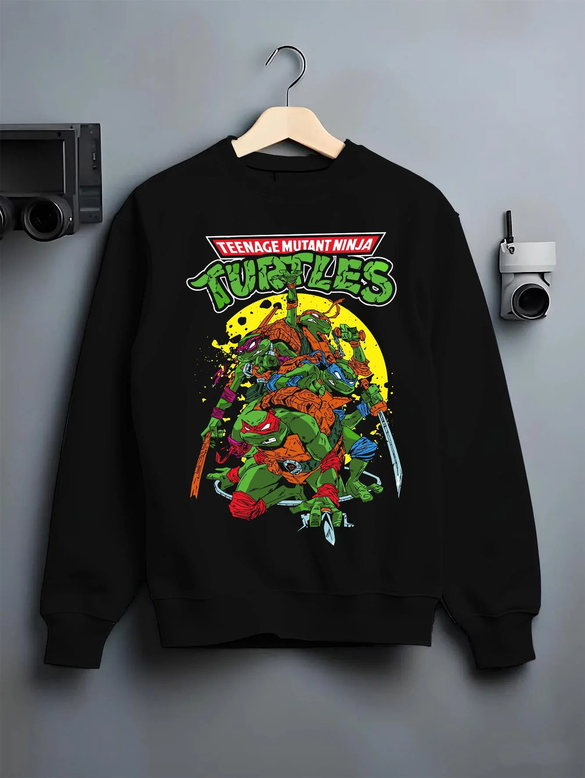Black crewneck sweatshirt on hanger featuring Teenage Mutant Ninja Turtles heroes TMNT artwork.