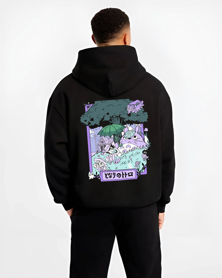 Black hoodie model back view showing Totoro and friends from My Neighbour Totoro: pastel forest scene