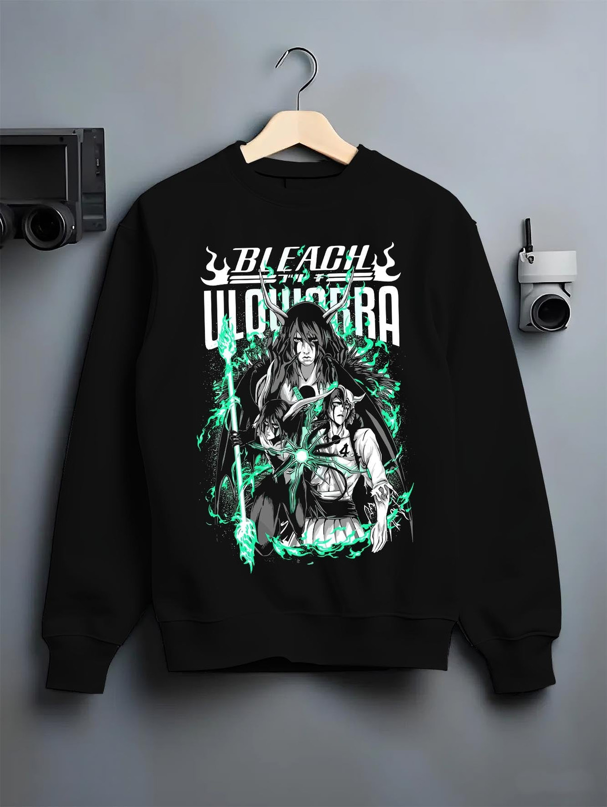 Black crewneck sweatshirt on a hanger against a grey wall, featuring Bleach Ulquiorra shonen battle inspired manga panel artwork with neon retro tones.