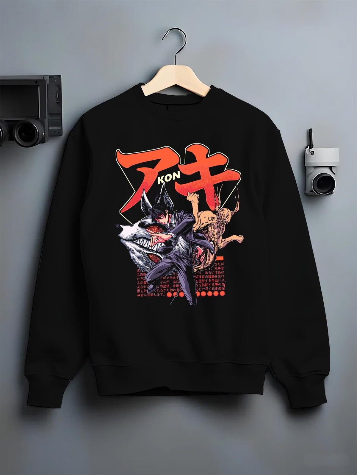 Black crewneck sweatshirt on a hanger against a grey wall, featuring Aki Chainsaw Man retro streetwear graphic with fox devil and vintage manga battle artwork.