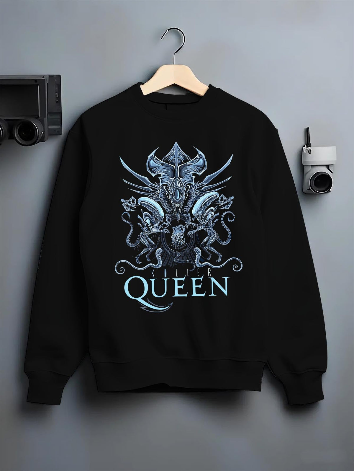 Black crewneck sweatshirt on hanger against grey wall, Alien Xenomorph Queen “Killer Queen” retro sci-fi back graphic with cool blue highlights.