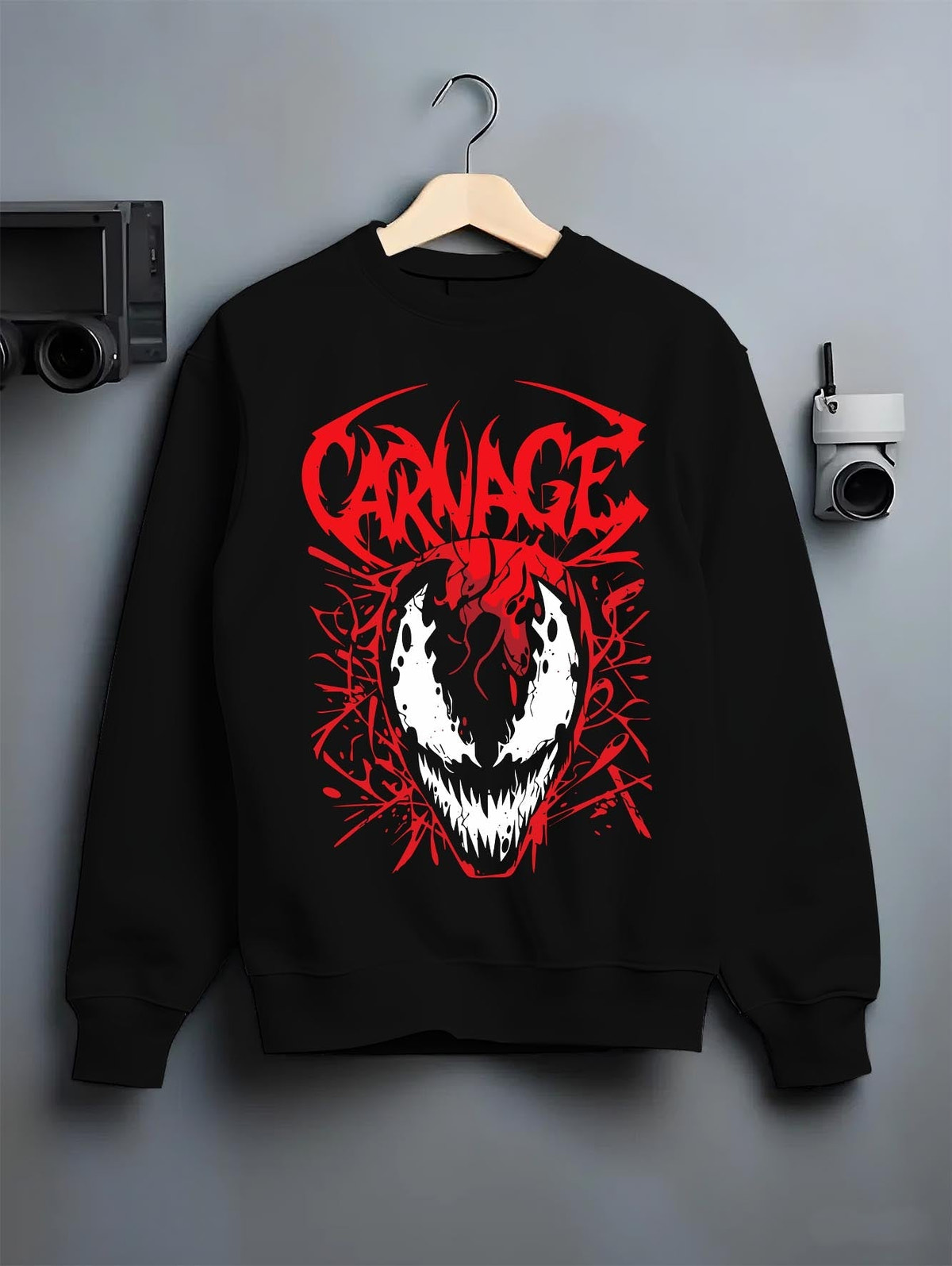 Black crewneck sweatshirt on hanger against grey wall, Carnage comic villain mask with red symbiote tendrils and bold graffiti logo.
