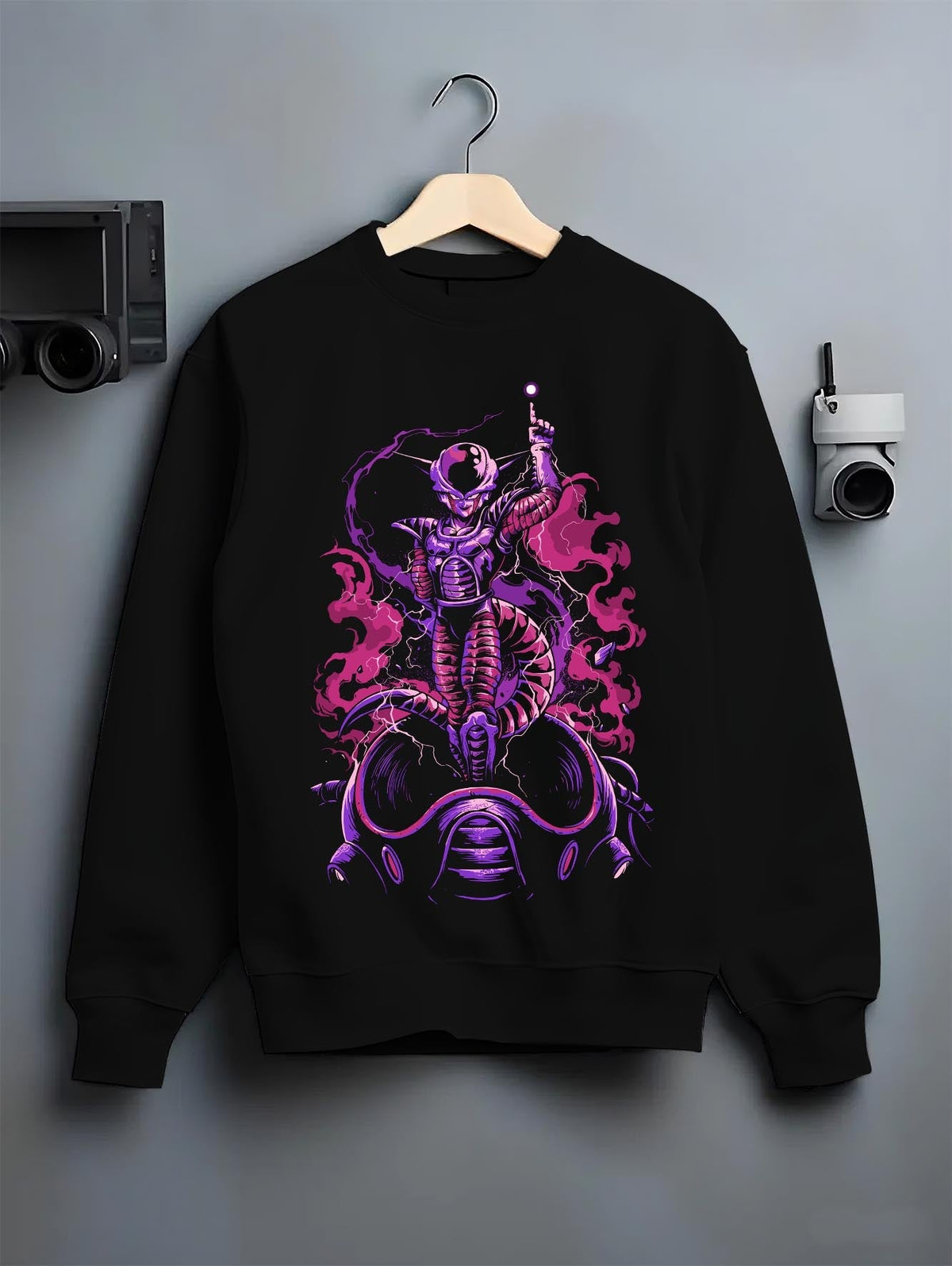 Black crewneck sweatshirt on a hanger against a grey wall, featuring Frieza Dragon Ball anime graphic with retro manga panel style and purple vaporwave aesthetic.