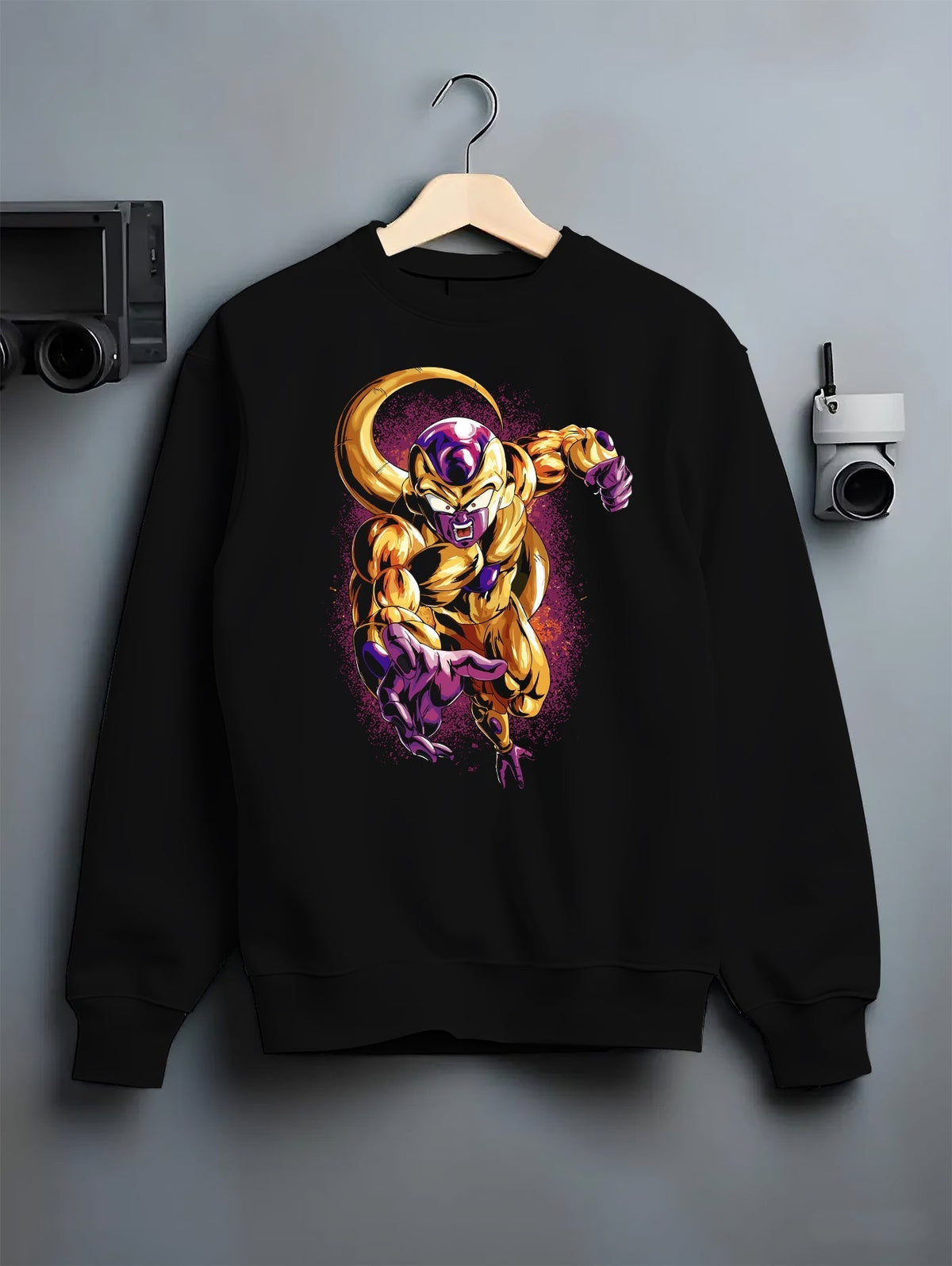 Black crewneck sweatshirt on a hanger against a grey wall, featuring Frieza Golden Form Dragon Ball Z retro manga graphic with glowing purple aura and bold villain artwork.
