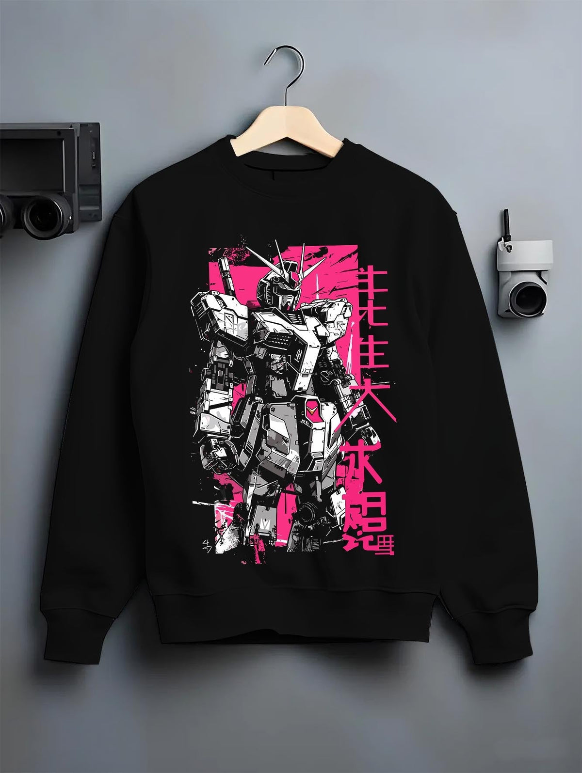Black crewneck sweatshirt on hanger against grey wall, showing Gundam retro mecha back graphic with pink poster style and Japanese lettering.