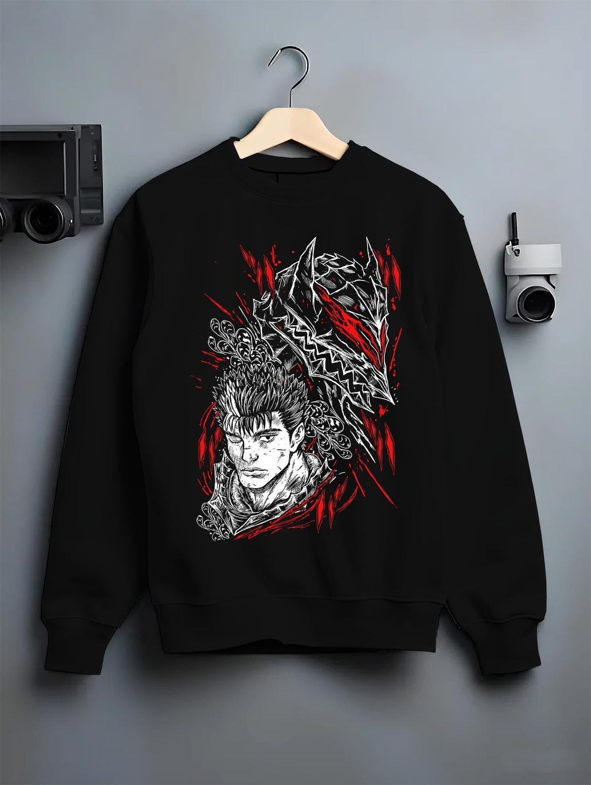 Black crewneck sweatshirt on a hanger against a grey wall, featuring Guts Berserk anime poster inspired design with manga panel graphic in striking red accents.