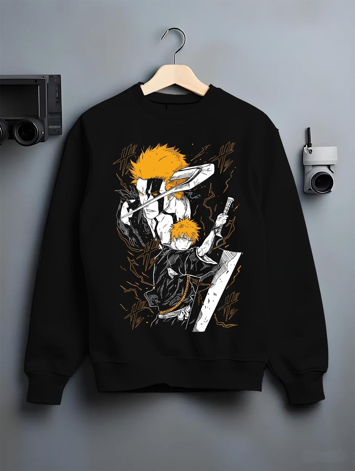 Black crewneck sweatshirt on a hanger against a grey wall, featuring Ichigo Bleach anime poster inspired design with shonen battle manga art in retro tones.