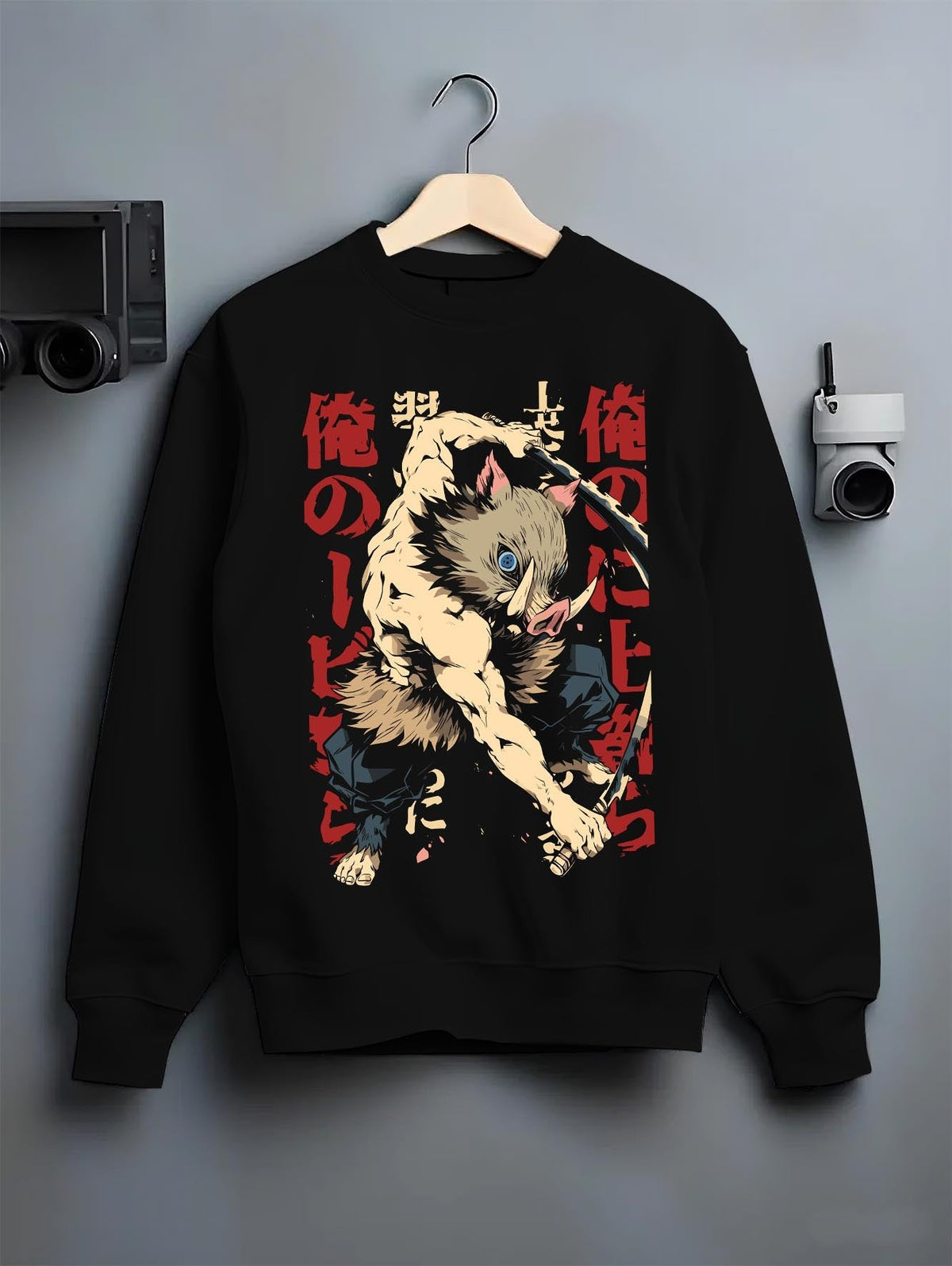 Black crewneck sweatshirt on a hanger against a grey wall, featuring Inosuke Demon Slayer retro streetwear graphic with bold boar mask warrior in battle design.