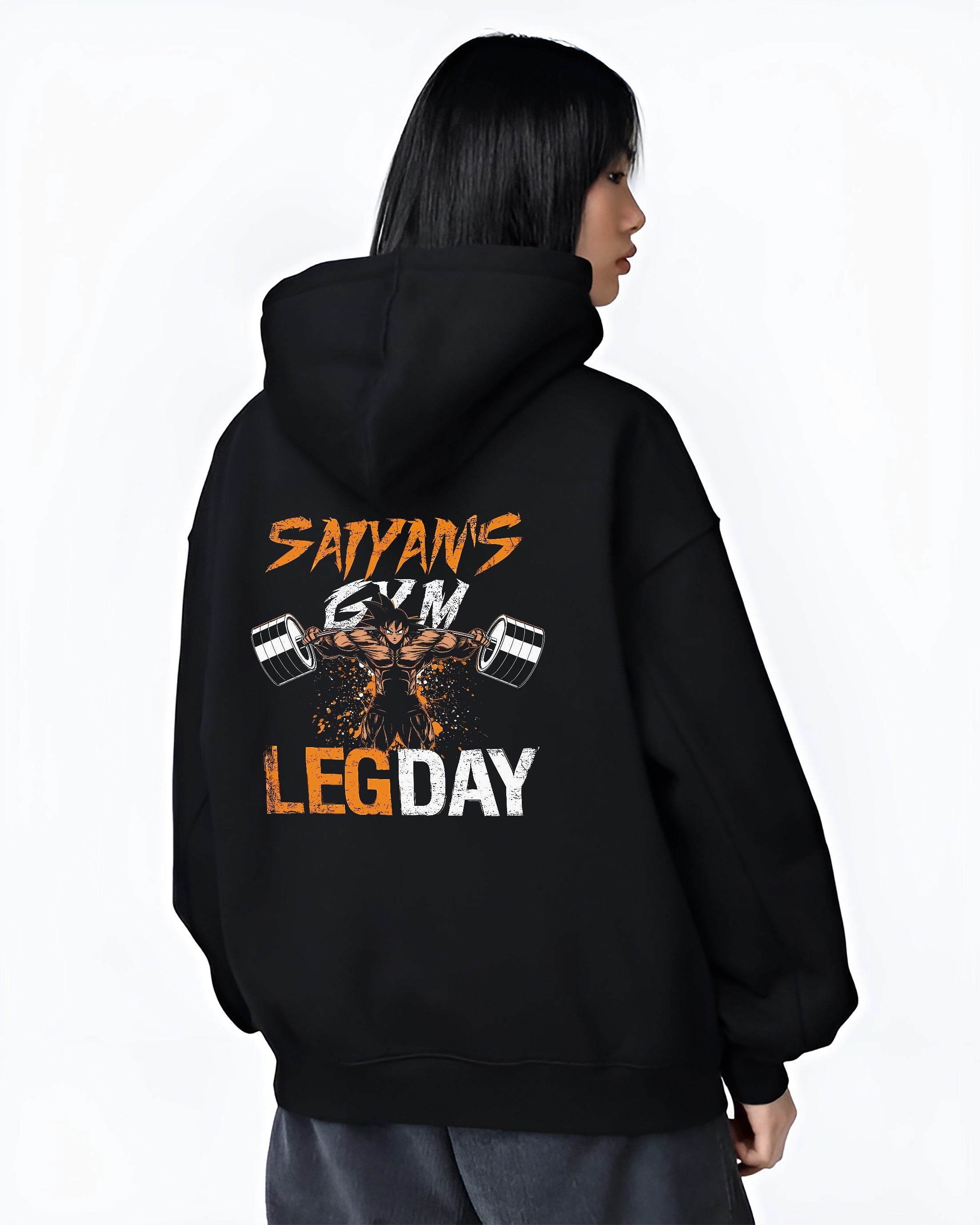 Black hoodie worn by a female model, back view, featuring Saiyan’s Gym Leg Day Japanese animation streetwear graphic with powerful gym character lifting heavy barbells.