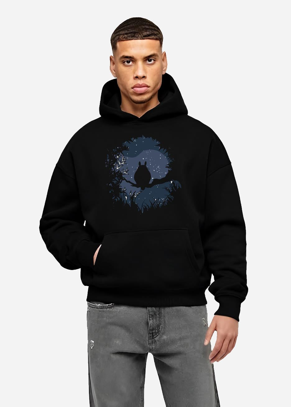 Black hoodie worn by a male model, back view, featuring Totoro night forest silhouette, anime poster inspired moon-and-stars minimalist graphic.