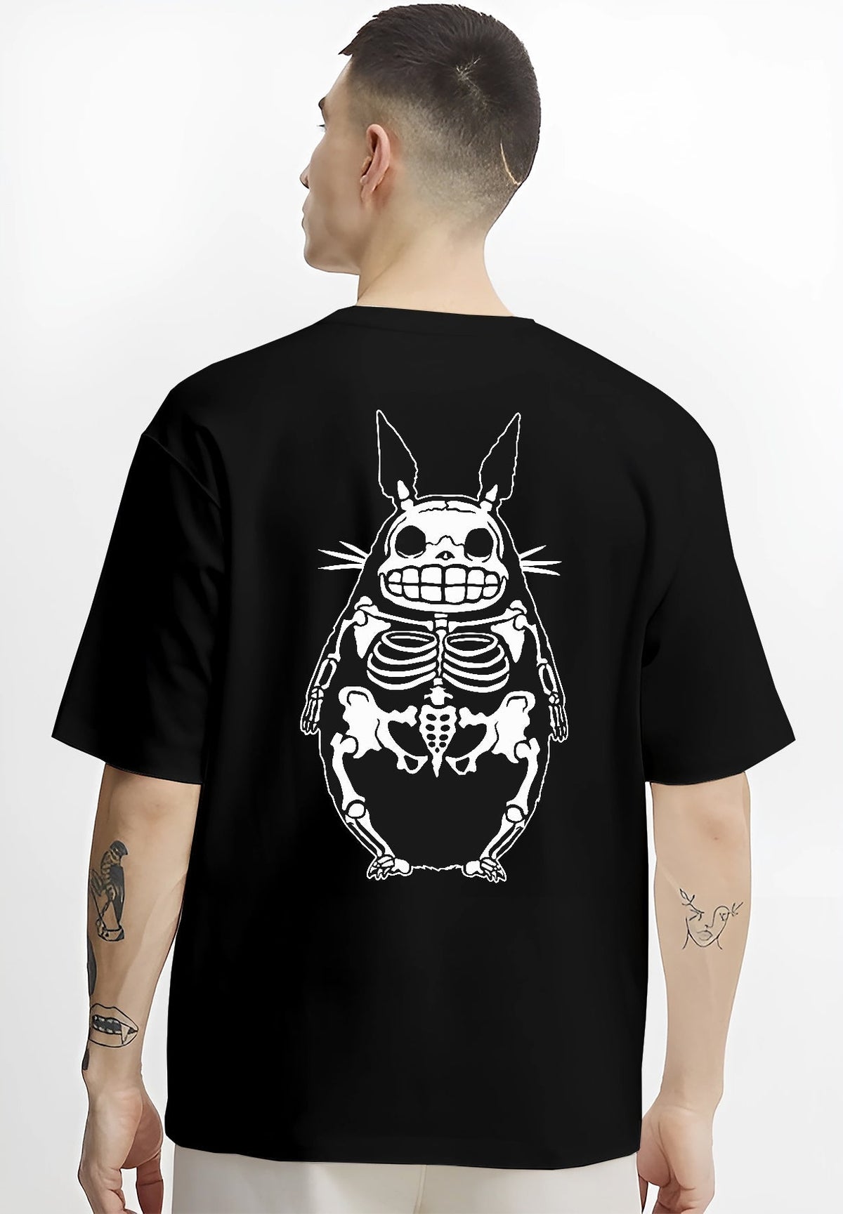 Black T-shirt worn by a male model, back view, featuring Totoro x-ray skeleton graphic, minimalist streetwear look with retro manga vibe.