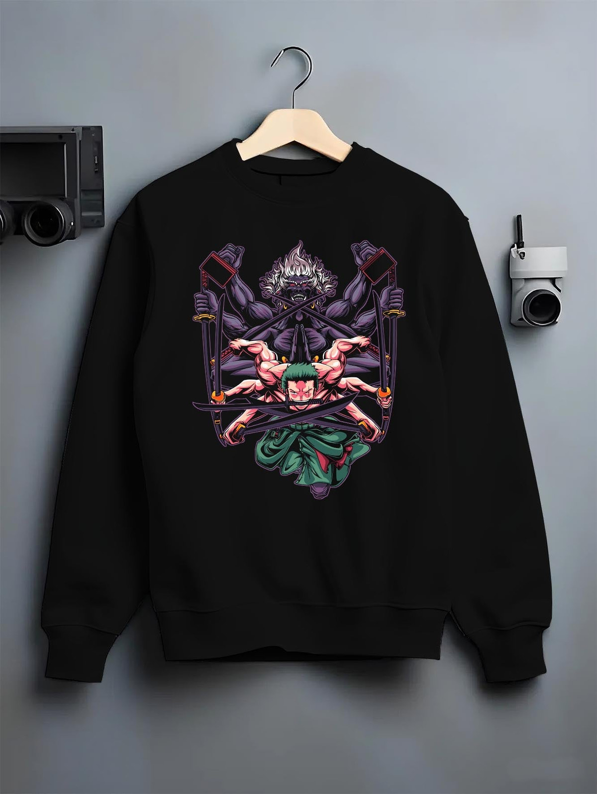 Black crewneck sweatshirt on a hanger against a grey wall, featuring Zoro One Piece retro streetwear graphic with demon aura and manga-inspired three-sword battle art.
